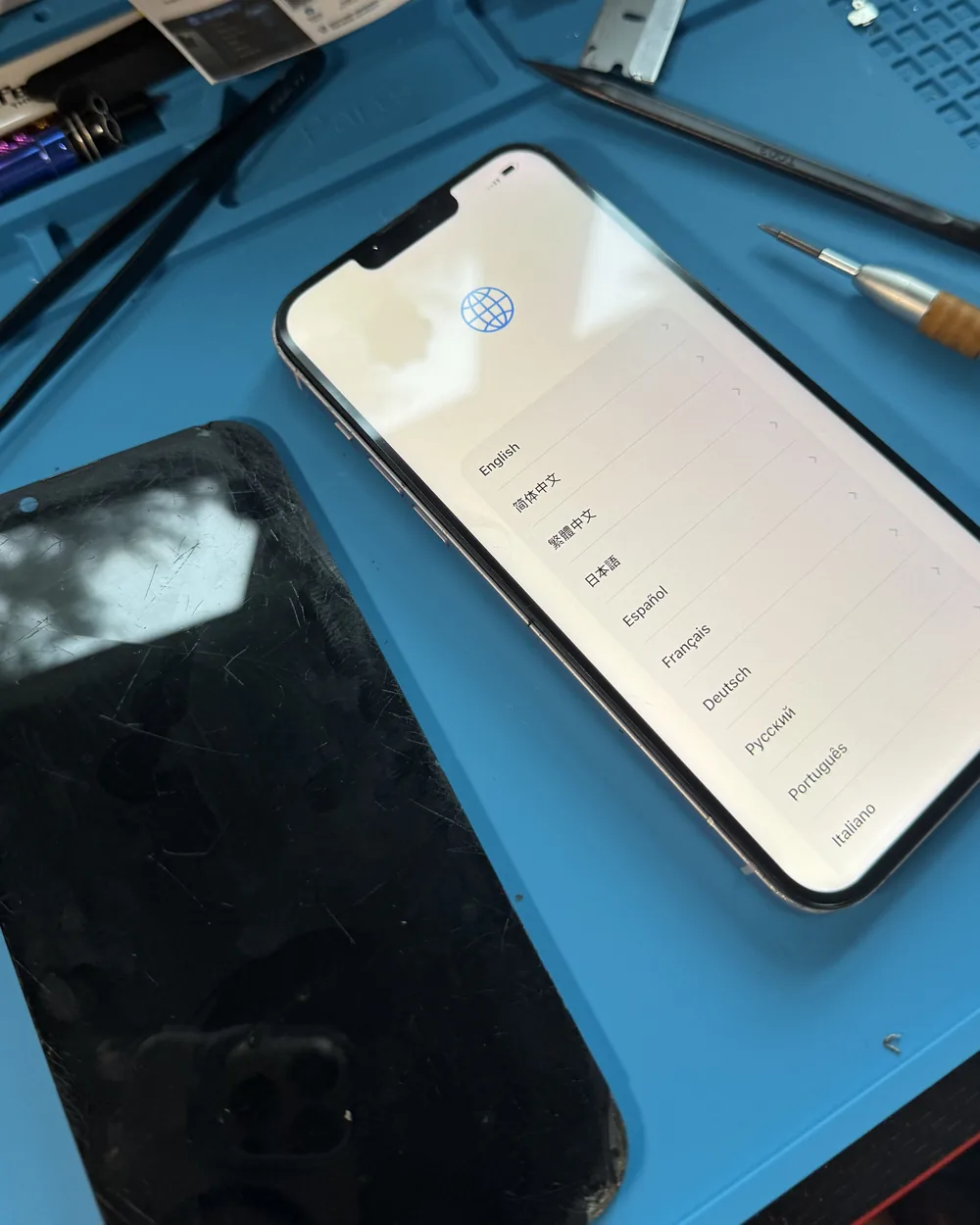 Repaired iPhone 15 Pro powered on next to its old, damaged screen after a screen replacement by Mobile Fix VA