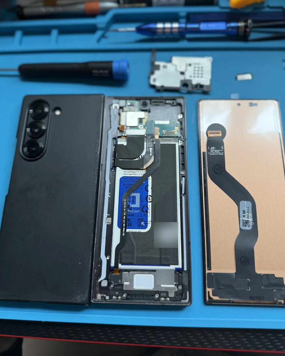 Disassembled Samsung Galaxy Z Fold during a screen replacement by Mobile Fix VA, showing the internal components and new screen module