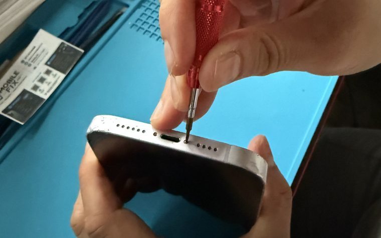 Technician working on an iPhone charging port with a precision screwdriver